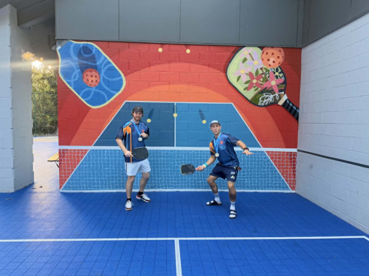 Two players in front of pickleball mural