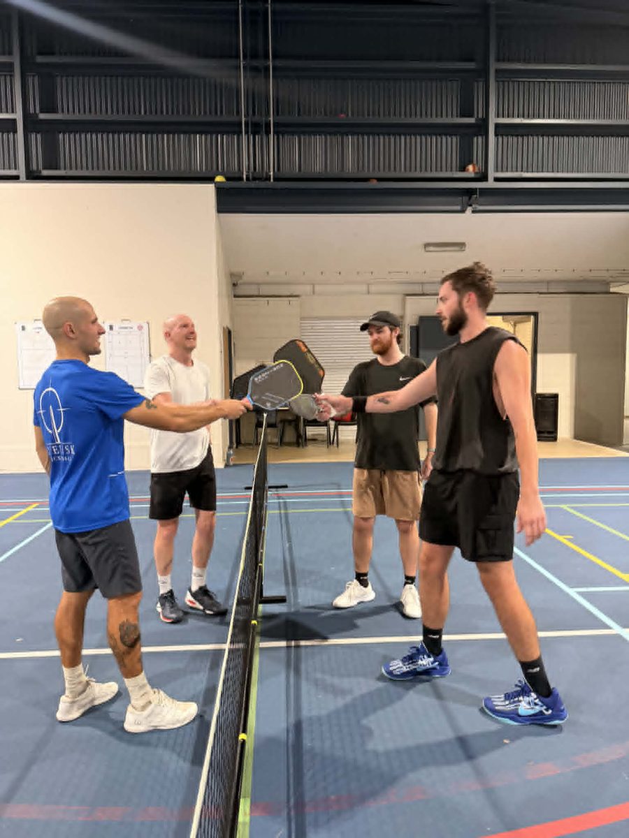 Players tapping paddles at the net